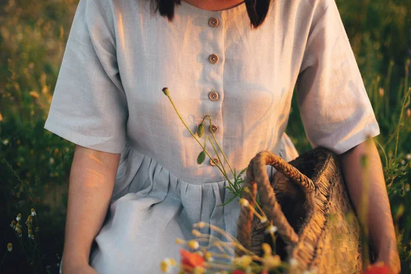 Стильная девушка в льняном платье собирает цветы в деревенской соломенной ба — стоковое фото