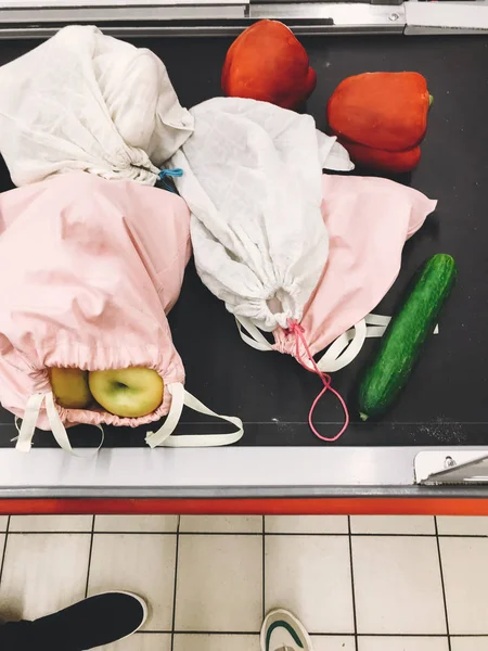 Groceries in eco friendly reusable bags on checkout counter line — Stock Photo, Image