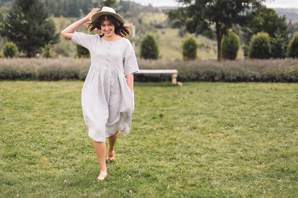 Stijlvolle hipster meisje in linnen jurk en hoed met plezier op lavend — Stockfoto