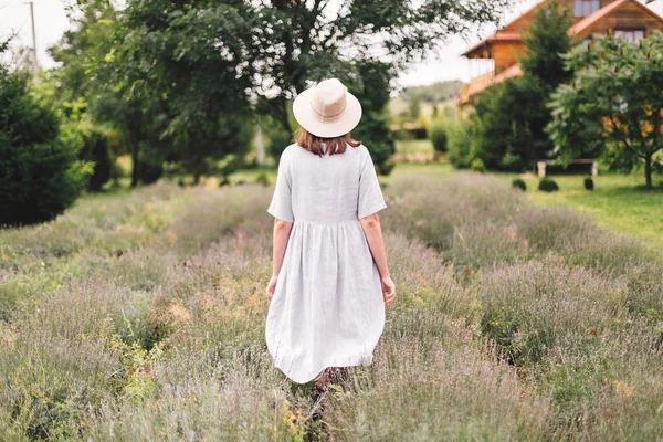 Stílusos csípő lány vászon ruha és kalap séta a levendula — Stock Fotó