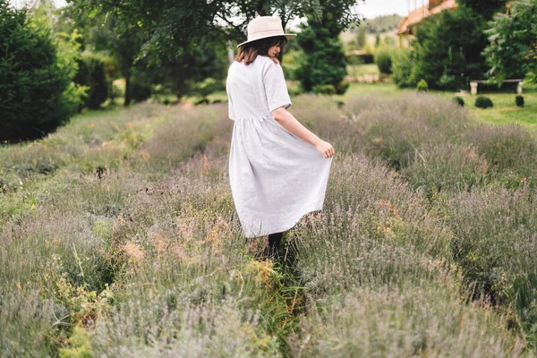 Elegante chica hipster en vestido de lino y sombrero caminando en lavanda — Foto de Stock