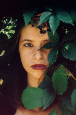 Yeşil yapraklar, atmosferik an poz şık hipster kız.