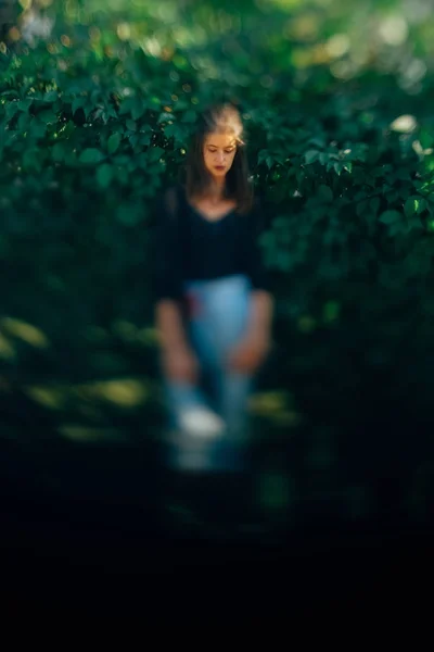 Стильна дівчина-хіпстер позує на зелене листя куща, атмосферний мо — стокове фото