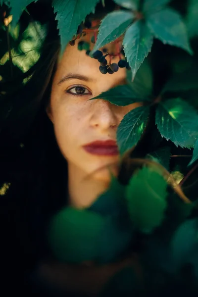 Stylish hipster girl posing at green leaves, atmospheric moment. — Stock Photo, Image