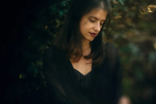 Élégant hipster fille posant à vert feuilles buisson, atmosphérique mo — Photo