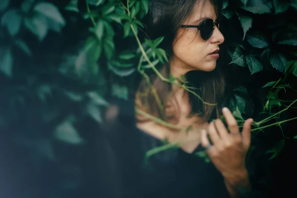 Stylish hipster girl posing at green leaves, atmospheric moment. — Stock Photo, Image