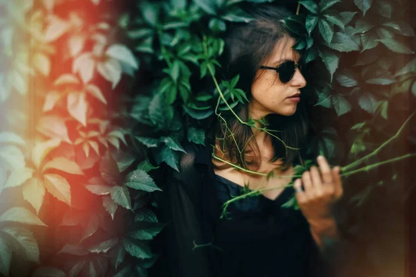 Stijlvolle hipster meisje poseren op groene bladeren, atmosferisch moment. — Stockfoto