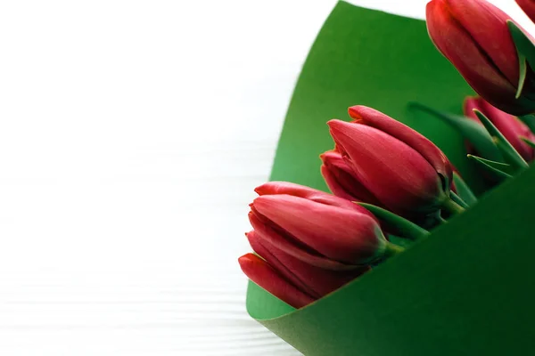 Belo buquê de tulipas rosa em papel verde sobre bac de madeira branca — Fotografia de Stock