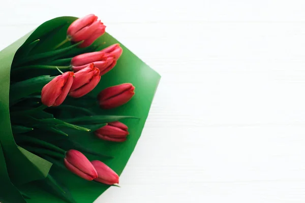 Belo buquê de tulipas rosa em papel verde sobre bac de madeira branca — Fotografia de Stock