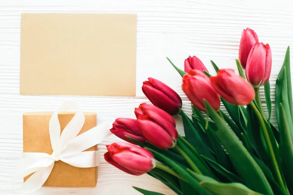 Hermosos tulipanes rojos con caja de regalo y tarjeta artesanal con espacio para — Foto de Stock