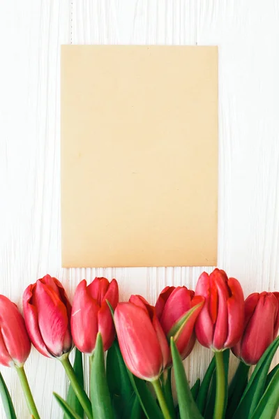 Красиві червоні тюльпани і реміснича листівка з місцем для тексту на білому — стокове фото
