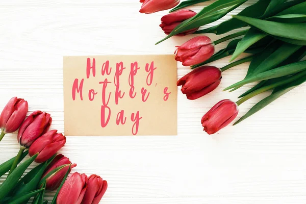 Ευτυχισμένο το κείμενο της μητέρας ημέρας και όμορφες κόκκινες τουλίπες σε λευκό ξύλινο — Φωτογραφία Αρχείου