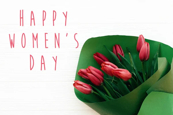 Fröhlicher Frauentagstext und schöne rote Tulpen auf weißem Holz — Stockfoto
