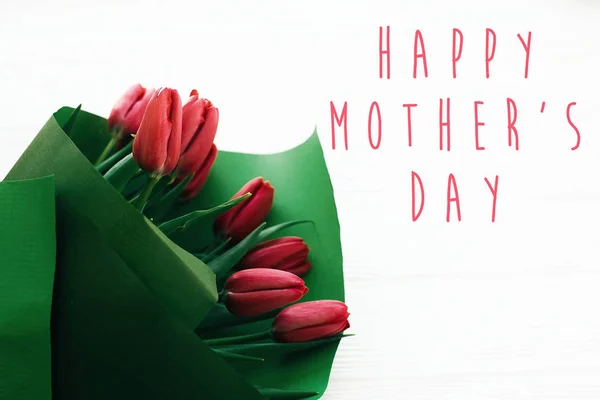 Szczęśliwy tekst dzień matki i piękne czerwone tulipany na białym drewnianym — Zdjęcie stockowe