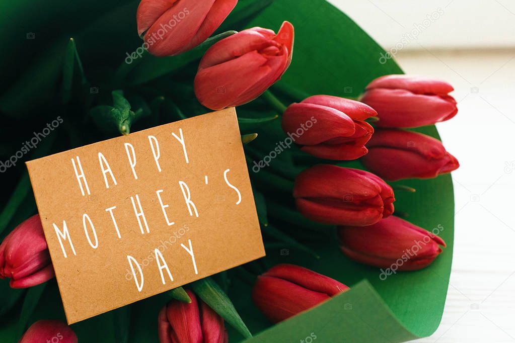 Happy Mother's Day text and beautiful red tulips on white wooden
