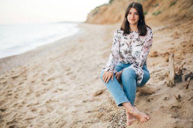 Denizde sahilde oturan şık hipster kız. Mutlu moda 