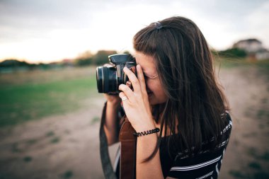 Şık hipster kız gün batımında sahilde fotoğraf çekmek. Yaz va