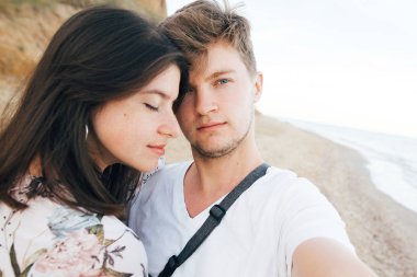 Şık hipster çift akşam denizde sahilde selfie çekiyor. Su