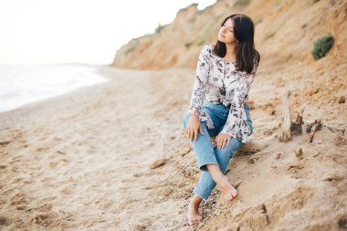 Denizde sahilde oturan şık hipster kız. Mutlu moda 