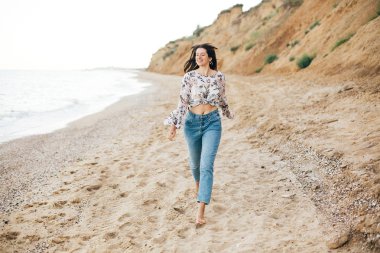 Şık hipster kız denizde sahilde çalışan ve gülümseyerek. Mutlu 