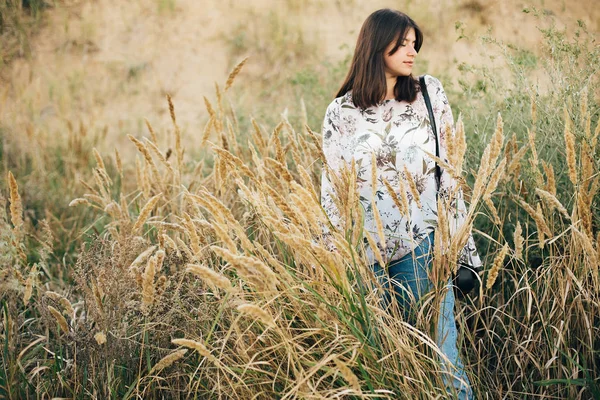 Elegante chica hipster posando en flores silvestres, hierbas largas en la playa — Foto de Stock