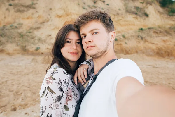 Elegante pareja hipster tomando selfie en la playa en el acantilado de arena en —  Fotos de Stock