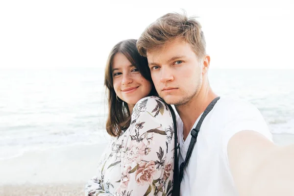 Elegante coppia hipster prendendo selfie sulla spiaggia al mare di sera. Su — Foto Stock