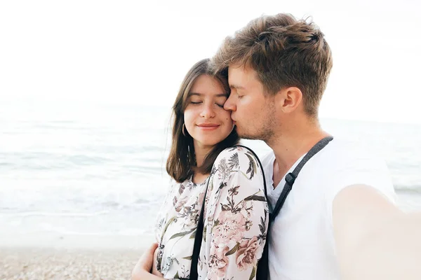 Elegante casal hipster tomando selfie na praia e beijando na véspera — Fotografia de Stock