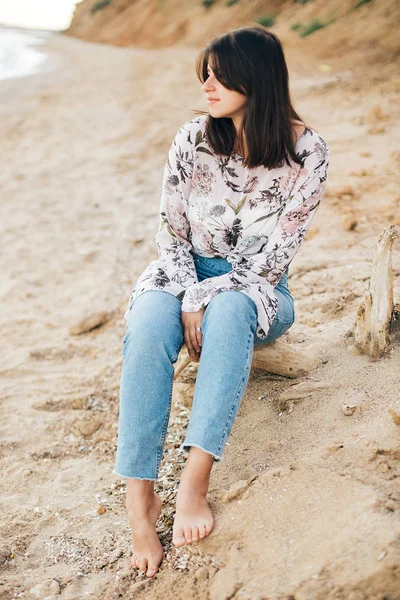 Denizde sahilde oturan şık hipster kız. Mutlu moda — Stok fotoğraf