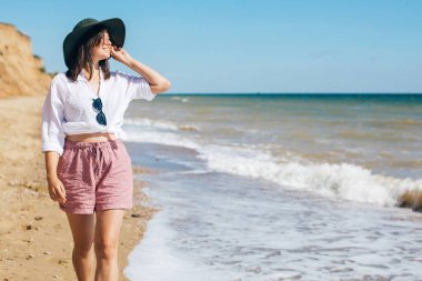 Mutlu genç boho kadın güneşli sıcak bir günde deniz dalgalarında yürüyüş