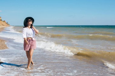 Mutlu genç boho kadın güneşli sıcak bir günde deniz dalgalarında yürüyüş