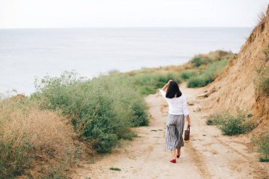 Tropik adada yürüyen beyaz gömlekli mutlu genç boho kadın