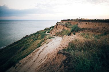 Güzel kumlu uçurum ve sakin deniz yüzeyi, gün batımında pembe gökyüzü 