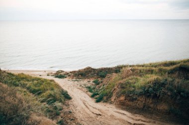 Sakin denize çim ve zemin yolu ile güzel kumlu uçurum. Olun