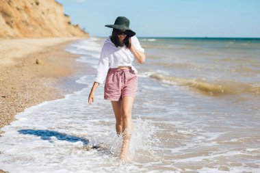 Mutlu genç boho kadın güneşli sıcak bir günde deniz dalgalarında yürüyüş