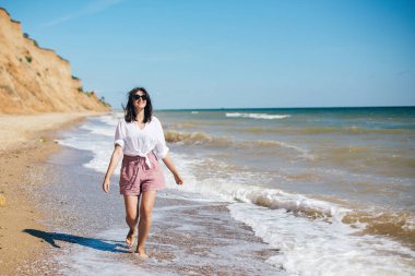 Mutlu genç boho kadın çalışan ve güneşli deniz dalgalarında gülümseyen