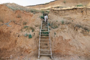 Şapka şık boho kız büyük kumlu c ahşap merdivenlerde oturan