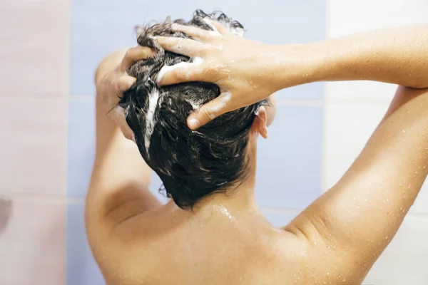 Молодая счастливая женщина моет волосы шампунем, руки пеной — стоковое фото