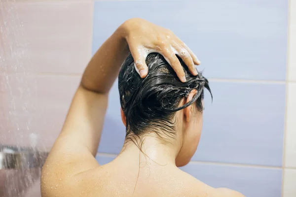 Joven mujer feliz lavándose el cabello con champú, espumoso con ha — Foto de Stock