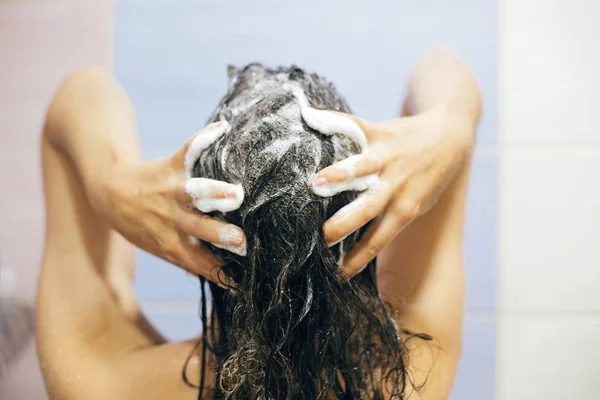 Młoda szczęśliwa kobieta myje włosy szamponem, ręce pianką — Zdjęcie stockowe