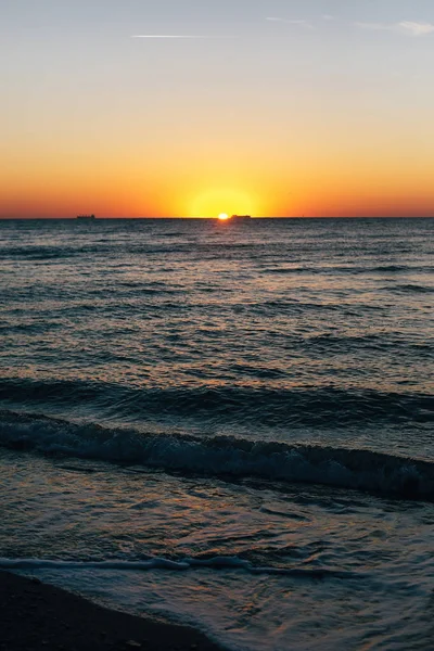 美丽的海浪泡沫特写和红色的天空与太阳在日出 — 图库照片