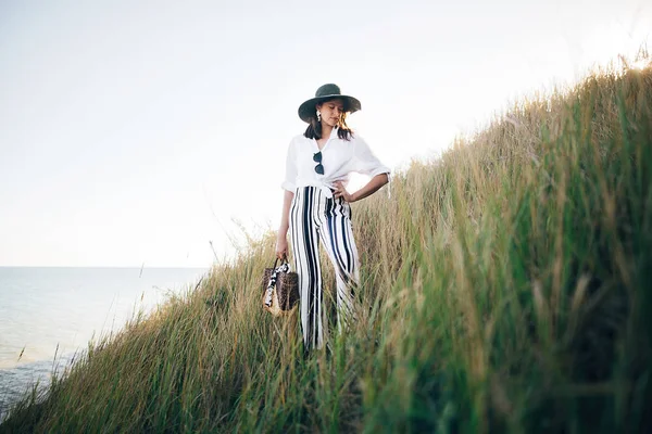 Stylisches Boho-Girl mit Hut posiert bei sonnigem Abend im Gras — Stockfoto