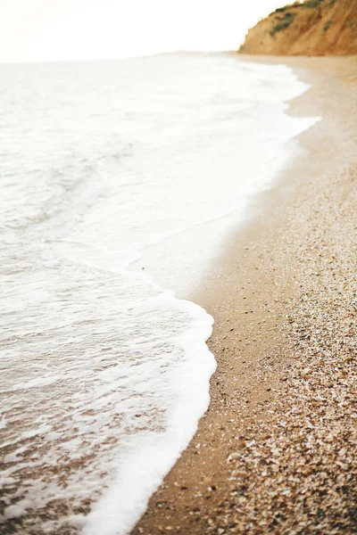 Bellissimo mare onde schiuma primo piano e spiaggia sabbiosa con conchiglie — Foto Stock