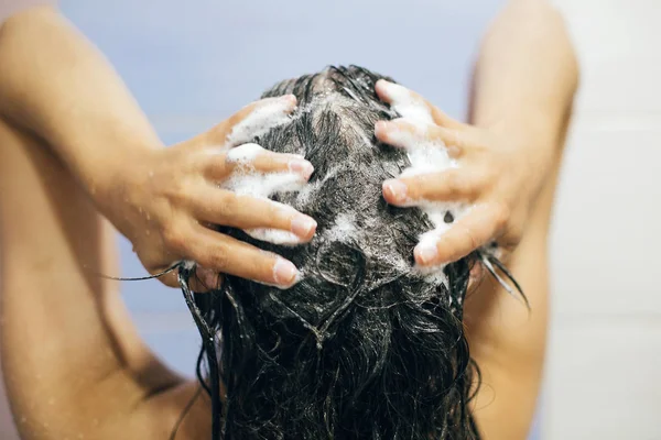 Jeune femme heureuse se lave les cheveux avec un shampooing, les mains avec de la mousse — Photo