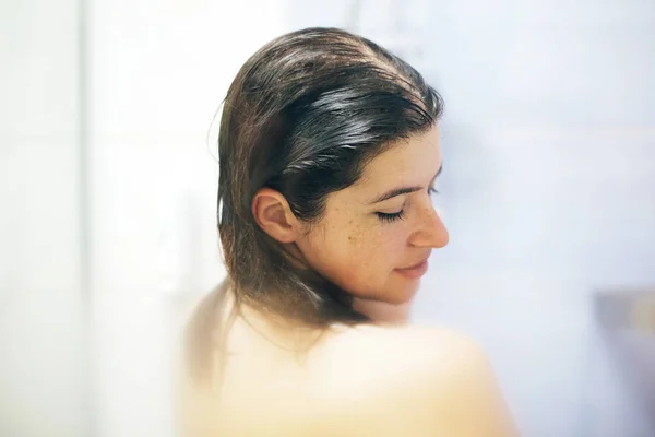 Young happy woman taking hot shower at home or hotel bathroom. B — Stock Photo, Image