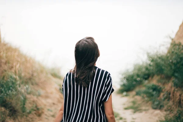 Stylische Hipster-Mädchen zu Fuß zum Meer zwischen sandigen Klippen mit gr — Stockfoto