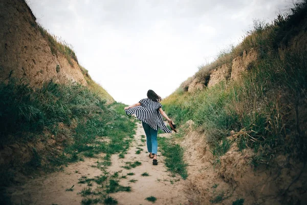 Stylové hipsterové děvče, které běží na písčitém útesu na moře a drží — Stock fotografie