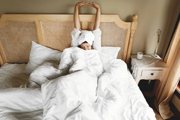 Belle jeune femme en serviette blanche se détendre au lit, profiter m — Photo
