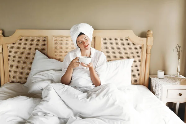 Belle jeune femme heureuse buvant du café au lit dans la chambre d'hôtel — Photo