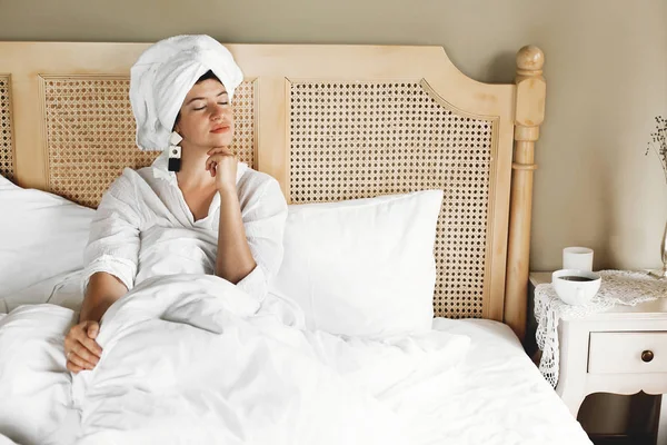 Élégante jeune femme heureuse se détendre au lit dans la chambre d'hôtel ou à la maison — Photo